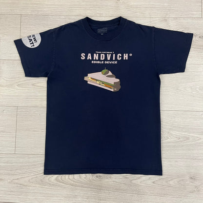 The Team Fortress 2 Sandvich 2010 Tee is an official Valve shirt released in December 2010 and produced during Valve’s in-house merch era. This Navy tee features a Sandvich Edible Device (Heavy secondary weapon) on the front, Sandvich blueprint graphic on the back and 'New Meat!' on the sleeve. A super rare collectible, it represents one of the original Valve Store releases from over a decade ago.