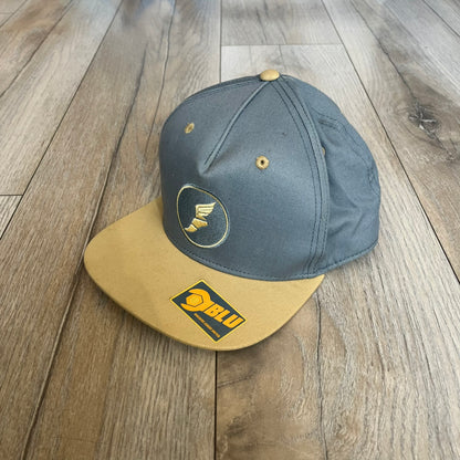 Team Fortress 2 Scout BLU LootCrate Hat is a blue and beige/yellow cap released with the 2016 LootCrate. The blue crown features an embroidered BLU Team Scout Hermes Boot logo, while the beige/yellow visor includes a BLU Team sticker and a large Team Fortress 2 logo on the underside. The hat combines official game branding with collectible LootCrate exclusivity.