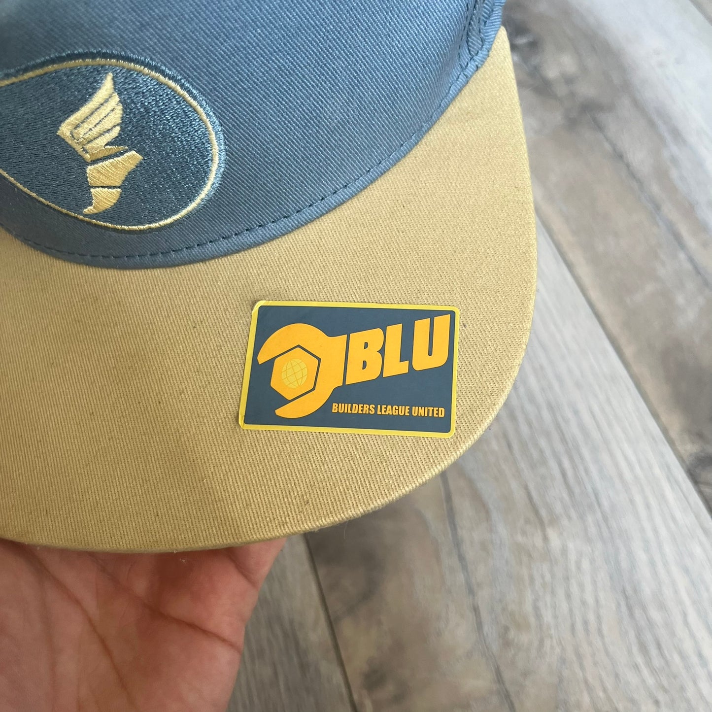 Team Fortress 2 Scout BLU LootCrate Hat is a blue and beige/yellow cap released with the 2016 LootCrate. The blue crown features an embroidered BLU Team Scout Hermes Boot logo, while the beige/yellow visor includes a BLU Team sticker and a large Team Fortress 2 logo on the underside. The hat combines official game branding with collectible LootCrate exclusivity.
