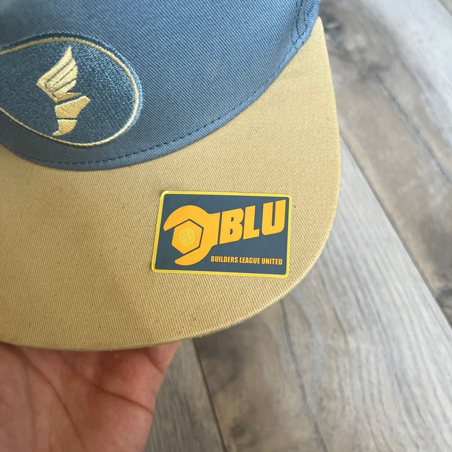 Team Fortress 2 Scout BLU LootCrate Hat is a blue and beige/yellow cap released with the 2016 LootCrate. The blue crown features an embroidered BLU Team Scout Hermes Boot logo, while the beige/yellow visor includes a BLU Team sticker and a large Team Fortress 2 logo on the underside. The hat combines official game branding with collectible LootCrate exclusivity.