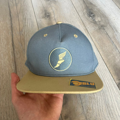 Team Fortress 2 Scout BLU LootCrate Hat is a blue and beige/yellow cap released with the 2016 LootCrate. The blue crown features an embroidered BLU Team Scout Hermes Boot logo, while the beige/yellow visor includes a BLU Team sticker and a large Team Fortress 2 logo on the underside. The hat combines official game branding with collectible LootCrate exclusivity.