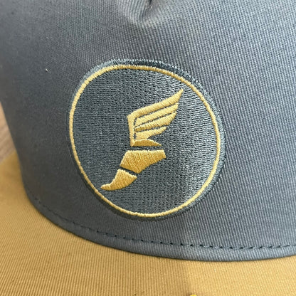 Team Fortress 2 Scout BLU LootCrate Hat is a blue and beige/yellow cap released with the 2016 LootCrate. The blue crown features an embroidered BLU Team Scout Hermes Boot logo, while the beige/yellow visor includes a BLU Team sticker and a large Team Fortress 2 logo on the underside. The hat combines official game branding with collectible LootCrate exclusivity.