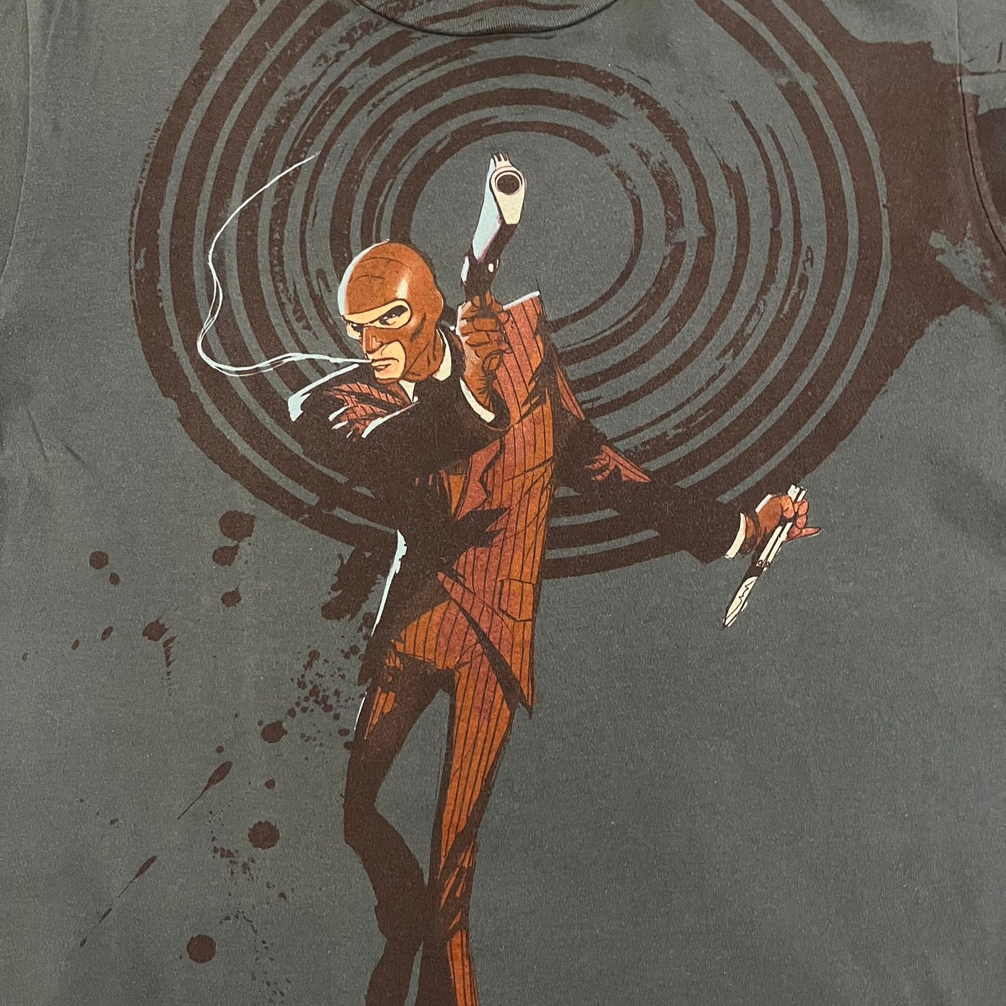 The Team Fortress 2 Spy 2009 Tee is an official Valve shirt from the Sniper vs. Spy update, produced during Valve’s in-house merch era before they switched to a different shirt company. This charcoal tee features a red Spy character holding a butterfly knife and gun, set against a dark red target graphic with dripping effects. A super rare collectible, it represents one of the original Valve Store releases from over a decade ago.