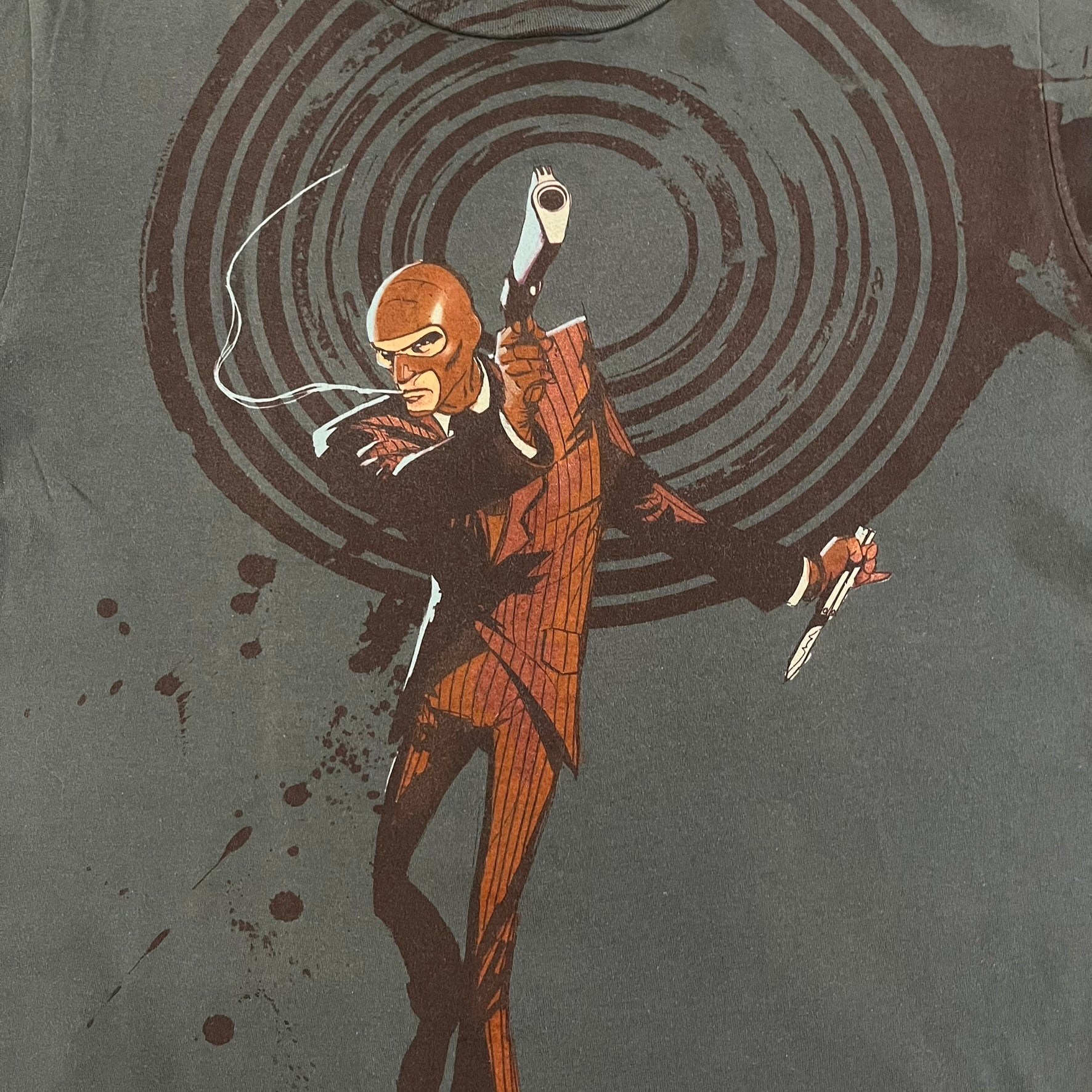 The Team Fortress 2 Spy 2009 Tee is an official Valve shirt from the Sniper vs. Spy update, produced during Valve’s in-house merch era before they switched to a different shirt company. This charcoal tee features a red Spy character holding a butterfly knife and gun, set against a dark red target graphic with dripping effects. A super rare collectible, it represents one of the original Valve Store releases from over a decade ago.