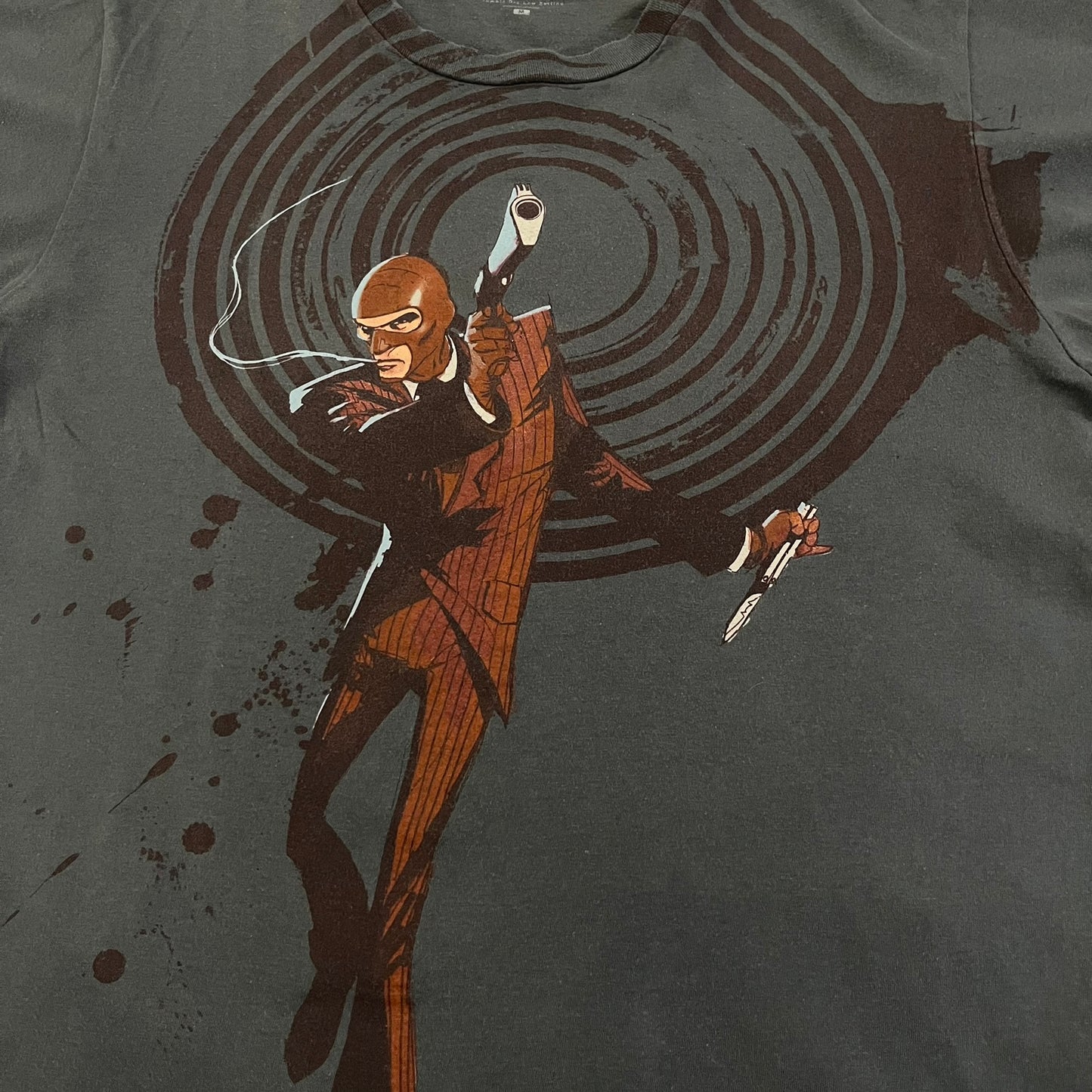 The Team Fortress 2 Spy 2009 Tee is an official Valve shirt from the Sniper vs. Spy update, produced during Valve’s in-house merch era before they switched to a different shirt company. This charcoal tee features a red Spy character holding a butterfly knife and gun, set against a dark red target graphic with dripping effects. A super rare collectible, it represents one of the original Valve Store releases from over a decade ago.
