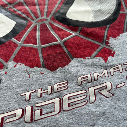 Gray 2014 Marvel tee featuring The Amazing Spider-Man 2 design with a “ripped page” effect showcasing Spider-Man’s face in the center. Text logo sits beneath the graphic for a bold cinematic touch. A collectible piece from the official movie merchandise line.