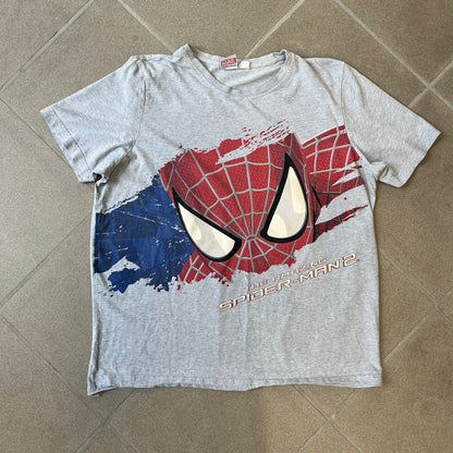 Gray 2014 Marvel tee featuring The Amazing Spider-Man 2 design with a “ripped page” effect showcasing Spider-Man’s face in the center. Text logo sits beneath the graphic for a bold cinematic touch. A collectible piece from the official movie merchandise line.