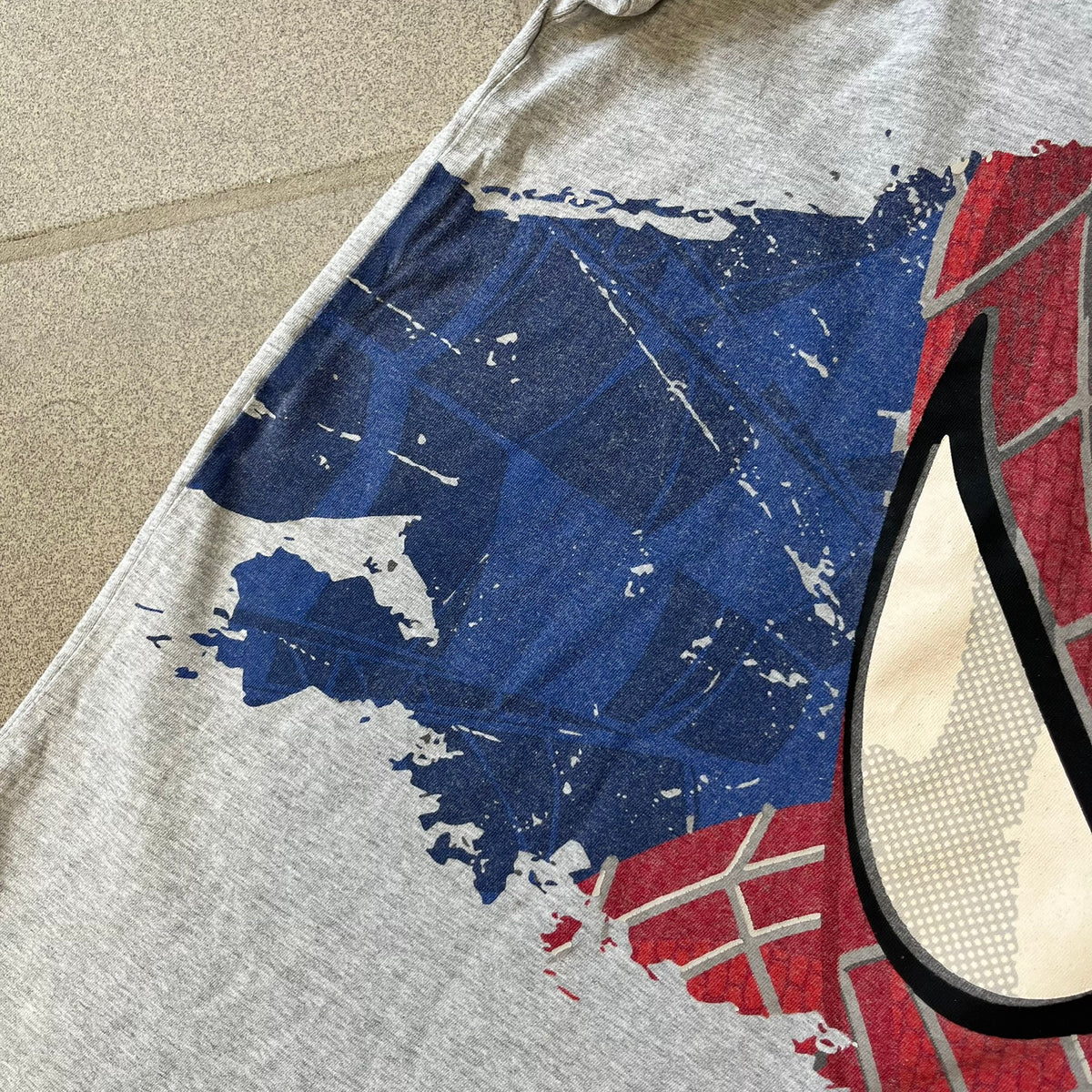 Gray 2014 Marvel tee featuring The Amazing Spider-Man 2 design with a “ripped page” effect showcasing Spider-Man’s face in the center. Text logo sits beneath the graphic for a bold cinematic touch. A collectible piece from the official movie merchandise line.