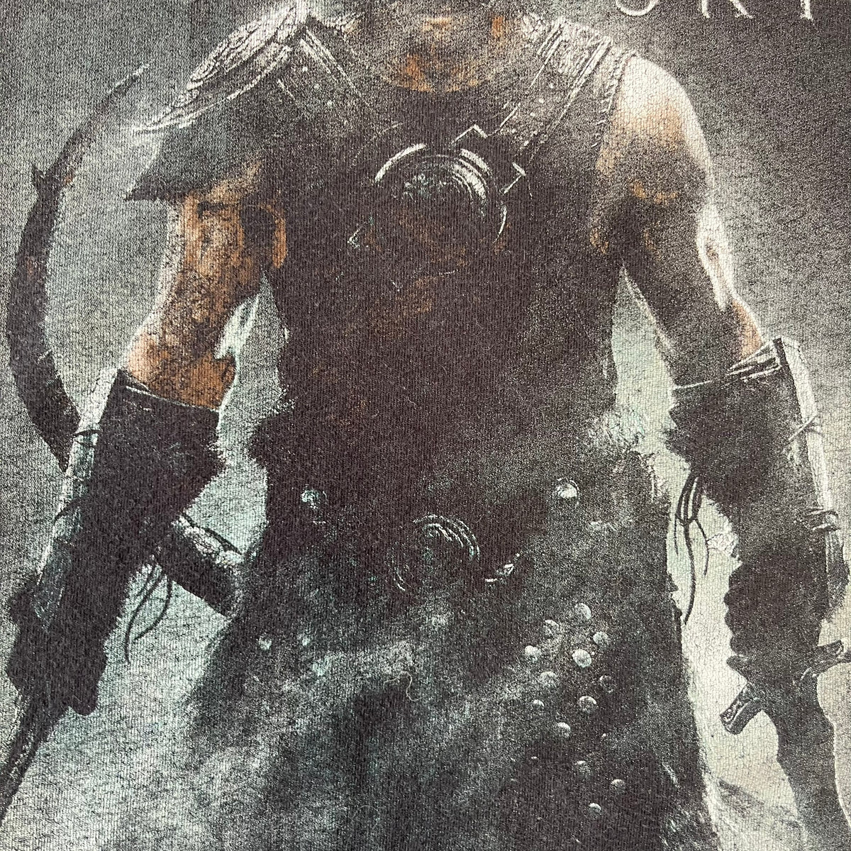 The Elder Scrolls V: Skyrim 2012 Dragonborn Tee features a black 100% cotton construction with the Dragonborn standing on top of a mountain, holding weapons and wearing a horned helmet. The Skyrim logo appears beside the character, with small white “@BSW” text underneath. Finished with a Bethesda licensed neck tag.
