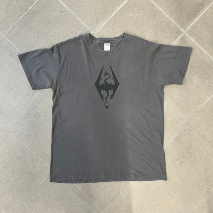 The Elder Scrolls V: Skyrim Premium Edition Tee comes from the 2012 Premium release of the game. Dark gray design with the Skyrim dragon logo printed on the front chest. The upper back has the full “The Elder Scrolls V: Skyrim” text. On the left sleeve there is a text in Dragon language. Made on a Gildan blank.