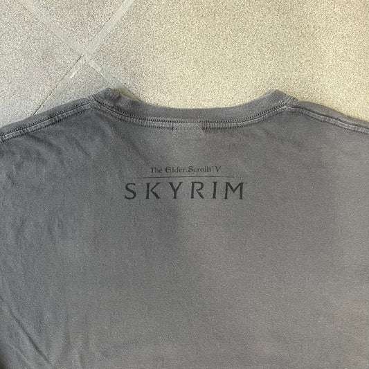 The Elder Scrolls V: Skyrim Premium Edition Tee comes from the 2012 Premium release of the game. Dark gray design with the Skyrim dragon logo printed on the front chest. The upper back has the full “The Elder Scrolls V: Skyrim” text. On the left sleeve there is a text in Dragon language. Made on a Gildan blank.