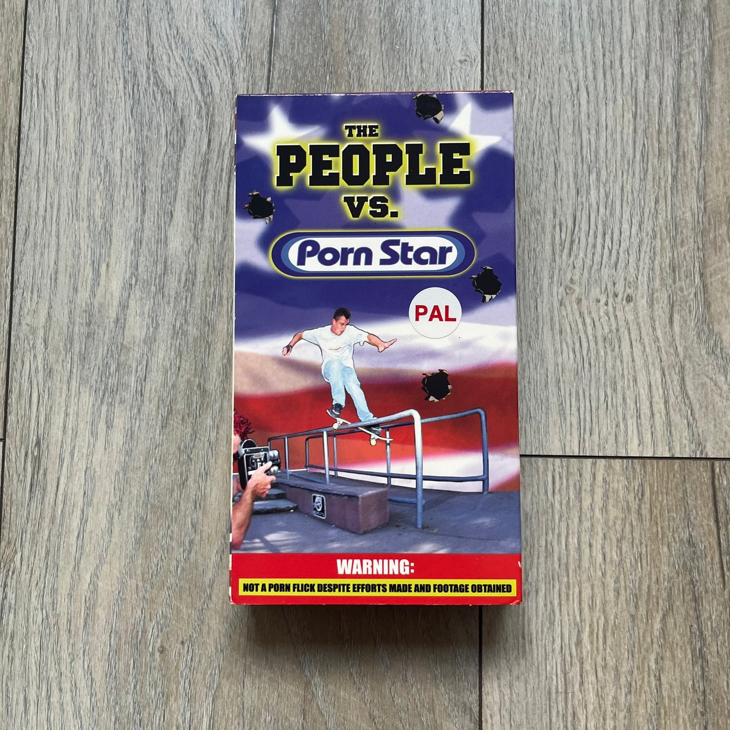 The People Vs. Porn Star is a 22-minute VHS video released in 2000 by Porn Star Skateboards in the United States. The tape features a mix of skate footage, live concert clips with featured artists, staged vignettes, and an on-camera segment with Sean “Vader” Murphy discussing the media attention surrounding the brand at the time. Original cover art includes the subtitle text “Not a Porn flick despite effort made and footage obtained” printed along the bottom.