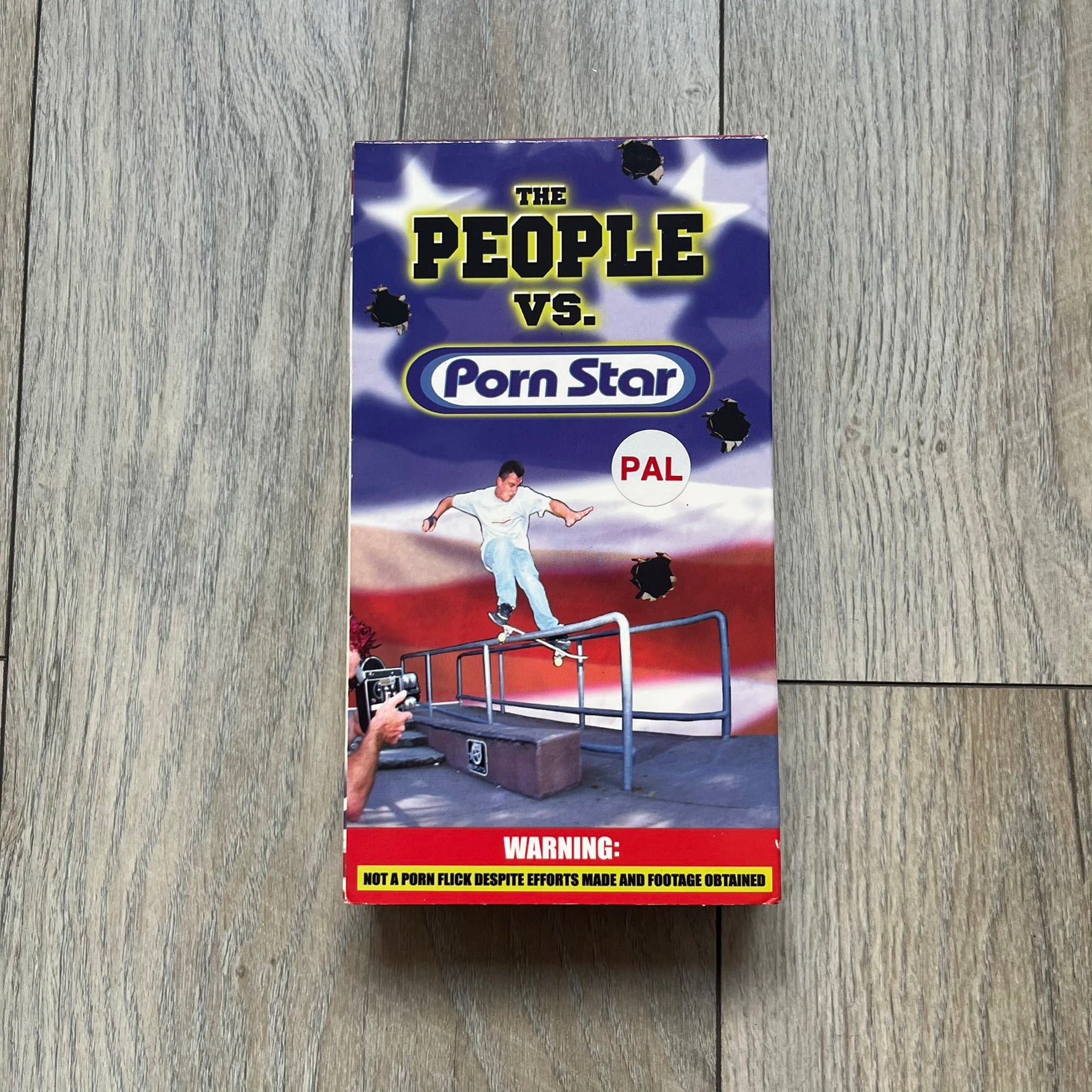 The People Vs. Porn Star is a 22-minute VHS video released in 2000 by Porn Star Skateboards in the United States. The tape features a mix of skate footage, live concert clips with featured artists, staged vignettes, and an on-camera segment with Sean “Vader” Murphy discussing the media attention surrounding the brand at the time. Original cover art includes the subtitle text “Not a Porn flick despite effort made and footage obtained” printed along the bottom.