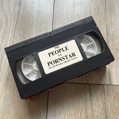 The People Vs. Porn Star is a 22-minute VHS video released in 2000 by Porn Star Skateboards in the United States. The tape features a mix of skate footage, live concert clips with featured artists, staged vignettes, and an on-camera segment with Sean “Vader” Murphy discussing the media attention surrounding the brand at the time. Original cover art includes the subtitle text “Not a Porn flick despite effort made and footage obtained” printed along the bottom.