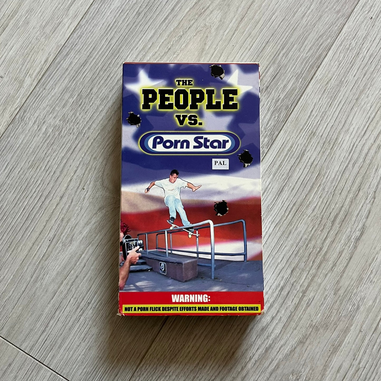 The People Vs. Porn Star is a 22-minute VHS video released in 2000 by Porn Star Skateboards in the United States. The tape features a mix of skate footage, live concert clips with featured artists, staged vignettes, and an on-camera segment with Sean “Vader” Murphy discussing the media attention surrounding the brand at the time. Original cover art includes the subtitle text “Not a Porn flick despite effort made and footage obtained” printed along the bottom.