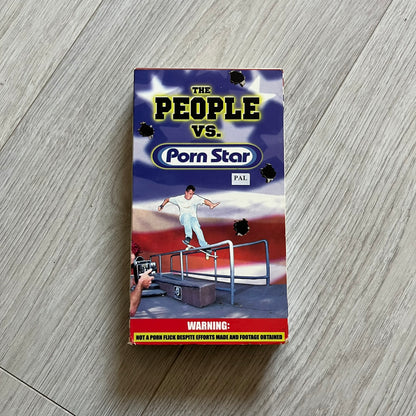 The People Vs. Porn Star is a 22-minute VHS video released in 2000 by Porn Star Skateboards in the United States. The tape features a mix of skate footage, live concert clips with featured artists, staged vignettes, and an on-camera segment with Sean “Vader” Murphy discussing the media attention surrounding the brand at the time. Original cover art includes the subtitle text “Not a Porn flick despite effort made and footage obtained” printed along the bottom.