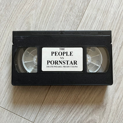 The People Vs. Porn Star is a 22-minute VHS video released in 2000 by Porn Star Skateboards in the United States. The tape features a mix of skate footage, live concert clips with featured artists, staged vignettes, and an on-camera segment with Sean “Vader” Murphy discussing the media attention surrounding the brand at the time. Original cover art includes the subtitle text “Not a Porn flick despite effort made and footage obtained” printed along the bottom.