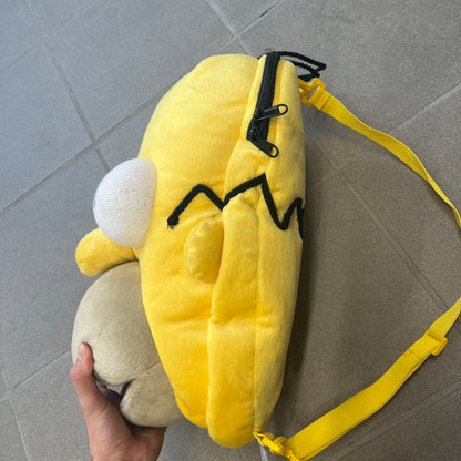 The Simpsons 1990s Homer Simpson Head Backpack is a novelty backpack shaped like a 3D Homer Simpson head. The design is fully yellow with soft sculpted facial features including eyes and nose, a molded mouth, and protruding ears. The hair detail wraps around the back, with the top strands functioning as a hanger. It includes yellow shoulder straps and a single main compartment.