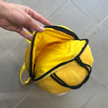 The Simpsons 1990s Homer Simpson Head Backpack is a novelty backpack shaped like a 3D Homer Simpson head. The design is fully yellow with soft sculpted facial features including eyes and nose, a molded mouth, and protruding ears. The hair detail wraps around the back, with the top strands functioning as a hanger. It includes yellow shoulder straps and a single main compartment.