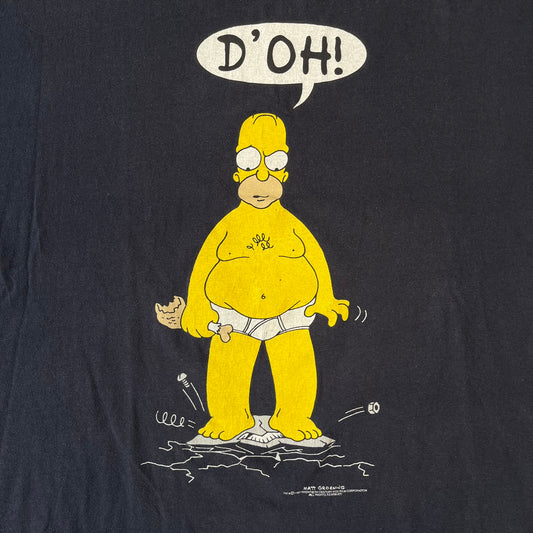 The Simpsons 1997 Homer “D’OH!” Black Tee features a black T-shirt with a front graphic of Homer Simpson standing in his underwear and looking down at a cracked scale while holding a chicken leg. A speech bubble above him reads “D’OH!”, with small Matt Groening 1997 licensing text underneath.
