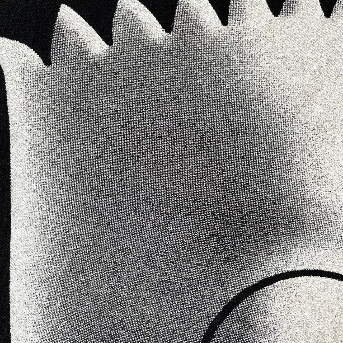 The Simpsons 1999 Bart Face Black Tee features a black T-shirt with a large front graphic of Bart Simpson’s face in black, grey, and white, showing a gritted-teeth expression. Small Matt Groening 1999 licensing text is printed below the graphic.
