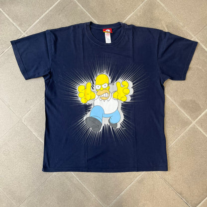 The Simpsons 2011 Angry Homer Navy Tee features a navy T-shirt with a front graphic of Homer Simpson running forward with an angry expression and reaching toward the viewer. The graphic has a grey glow-like background with small Matt Groening text beside Homer. Includes a 2011 licensed neck tag.
