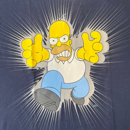 The Simpsons 2011 Angry Homer Navy Tee features a navy T-shirt with a front graphic of Homer Simpson running forward with an angry expression and reaching toward the viewer. The graphic has a grey glow-like background with small Matt Groening text beside Homer. Includes a 2011 licensed neck tag.
