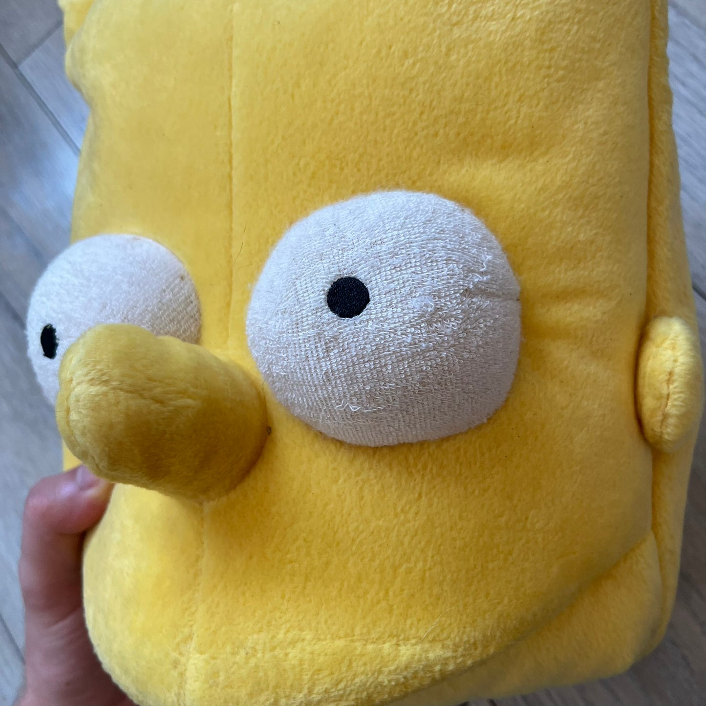 The Simpsons 1990's Bart Simpson Head Backpack is a novelty backpack shaped like a 3D Bart Simpson head. The design is fully yellow with soft sculpted facial features including eyes and nose, a molded mouth, and protruding hair. It includes yellow shoulder straps and a single main compartment.