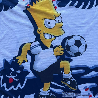 Officially licensed 1999 The Simpsons World Cup T-shirt for England. Lightweight white polyester tee featuring an all-over graphic design. The front shows Bart Simpson kicking a football, dressed in a white tee, with multiple England three-lions emblems layered across the background from top to bottom. Red “Bart” text details appear on the sleeve hems, with Matt Groening / The Simpsons ©1999 licensing printed beneath the main graphic.&nbsp;The back mirrors the artwork in a flipped layout, showing Bart from 
