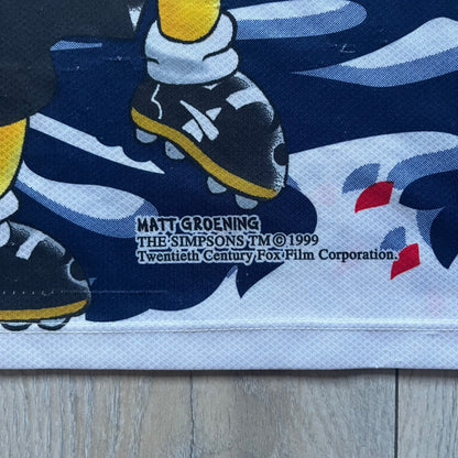 Officially licensed 1999 The Simpsons World Cup T-shirt for England. Lightweight white polyester tee featuring an all-over graphic design. The front shows Bart Simpson kicking a football, dressed in a white tee, with multiple England three-lions emblems layered across the background from top to bottom. Red “Bart” text details appear on the sleeve hems, with Matt Groening / The Simpsons ©1999 licensing printed beneath the main graphic.&nbsp;The back mirrors the artwork in a flipped layout, showing Bart from 