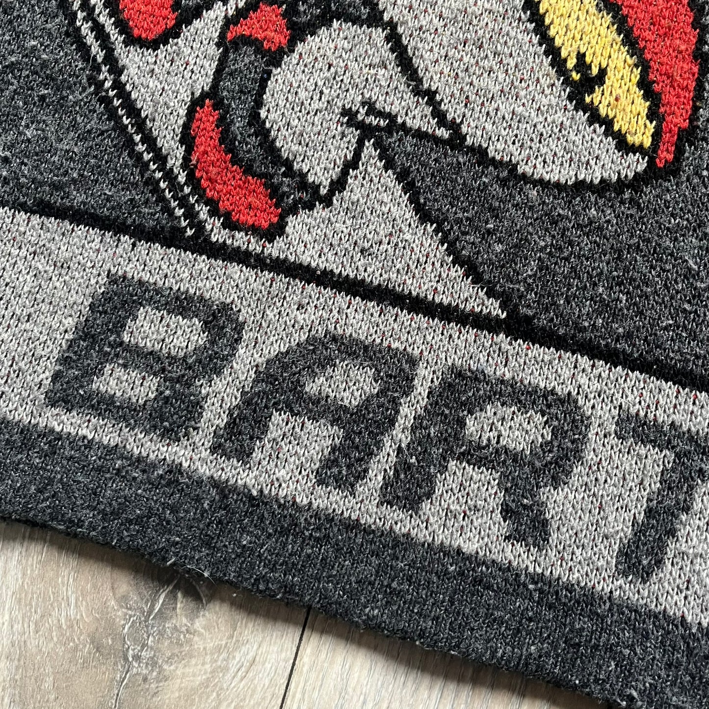 The Simpsons “Bart Freestyle” 2003 Knit Sweater is a gray knit featuring a large woven graphic of Bart snowboarding on the front, with “Bart” text placed below the character. On the back, in the same position as the front graphic, there is “Freestyle” text.&nbsp;It includes a Matt Groening The Simpsons 2003 FOX neck tag.