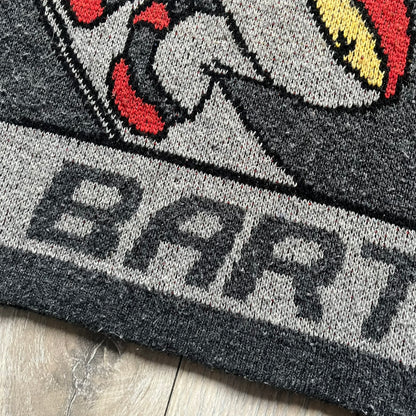 The Simpsons “Bart Freestyle” 2003 Knit Sweater is a gray knit featuring a large woven graphic of Bart snowboarding on the front, with “Bart” text placed below the character. On the back, in the same position as the front graphic, there is “Freestyle” text.&nbsp;It includes a Matt Groening The Simpsons 2003 FOX neck tag.