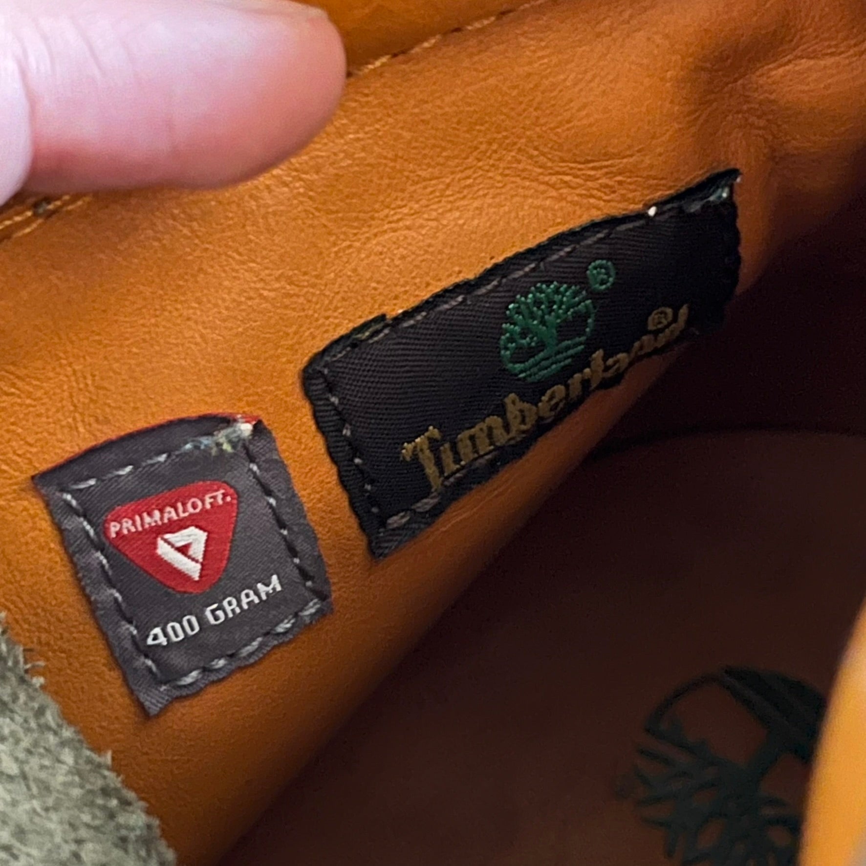 Timberland 6-Inch x Zoolander Olive Boots, model A1QTY / A2040. These collaboration boots feature an olive/army green upper with an orange metal Timberland logo on the side and an orange padded collar with large olive Timberland text. The laces are olive with small orange speckled details, matched by orange lace eyelets. This Zoolander collaboration was not sold in the United States and is considered extremely difficult to find.