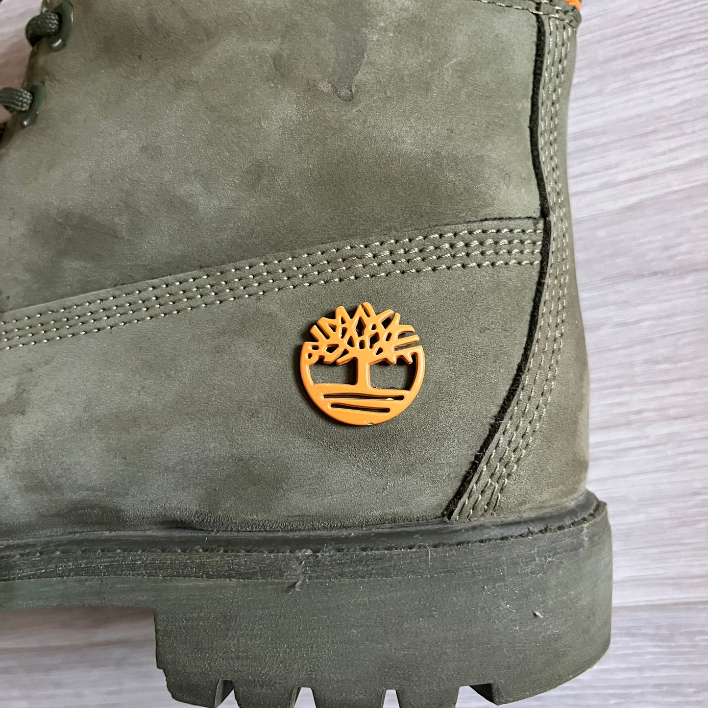 Timberland 6-Inch x Zoolander Olive Boots, model A1QTY / A2040. These collaboration boots feature an olive/army green upper with an orange metal Timberland logo on the side and an orange padded collar with large olive Timberland text. The laces are olive with small orange speckled details, matched by orange lace eyelets. This Zoolander collaboration was not sold in the United States and is considered extremely difficult to find.