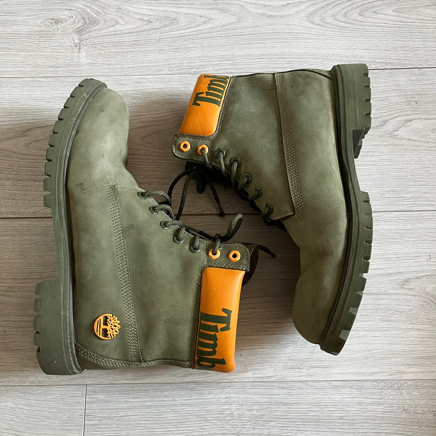 Timberland 6-Inch x Zoolander Olive Boots, model A1QTY / A2040. These collaboration boots feature an olive/army green upper with an orange metal Timberland logo on the side and an orange padded collar with large olive Timberland text. The laces are olive with small orange speckled details, matched by orange lace eyelets. This Zoolander collaboration was not sold in the United States and is considered extremely difficult to find.