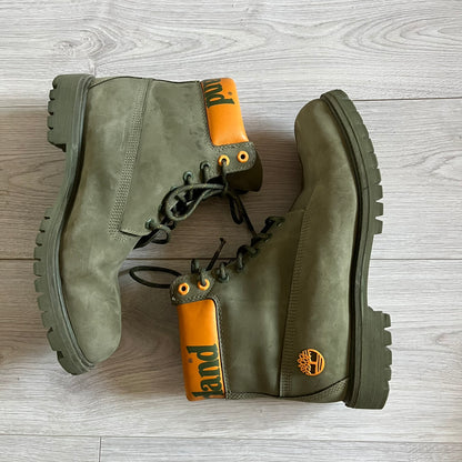 Timberland 6-Inch x Zoolander Olive Boots, model A1QTY / A2040. These collaboration boots feature an olive/army green upper with an orange metal Timberland logo on the side and an orange padded collar with large olive Timberland text. The laces are olive with small orange speckled details, matched by orange lace eyelets. This Zoolander collaboration was not sold in the United States and is considered extremely difficult to find.