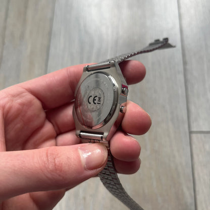 Timex x Maison Margiela MM6 Gift Set TWG065600 is a collaborative reinterpretation of the classic Timex T80, released on October 24, 2024. Crafted from polished and brushed stainless steel, it features a 36mm digital case with Timex branding and a distinctive 0–23 numeral layout, including a subtle circled “6” nod to MM6 design language. The watch offers 100 ft water resistance, mineral glass, backlight, alarm, timer, and date functions, and is presented as a 2-in-1 gift set with an additional standalone st