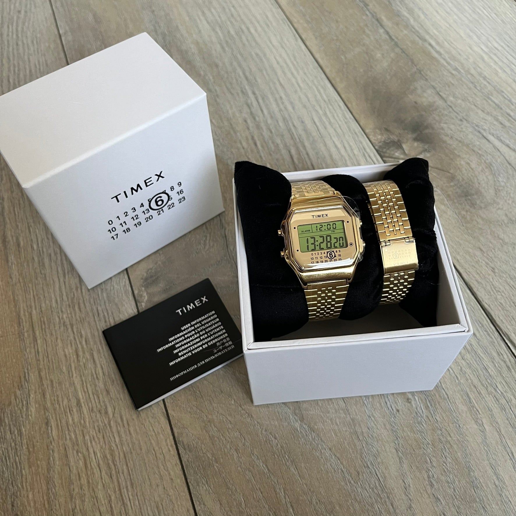 Timex x Maison Margiela MM6 Gold Watch + Bracelet Gift Set TWG067500QY is a collaborative reinterpretation of the classic Timex T80, released on October 24, 2024. Crafted from polished and brushed stainless steel, it features a 36mm digital case with Timex branding and a distinctive 0–23 numeral layout, including a subtle circled “6” nod to MM6 design language. The watch offers 100 ft water resistance, mineral glass, backlight, alarm, timer, and date functions, and is presented as a 2-in-1 gift set with an 