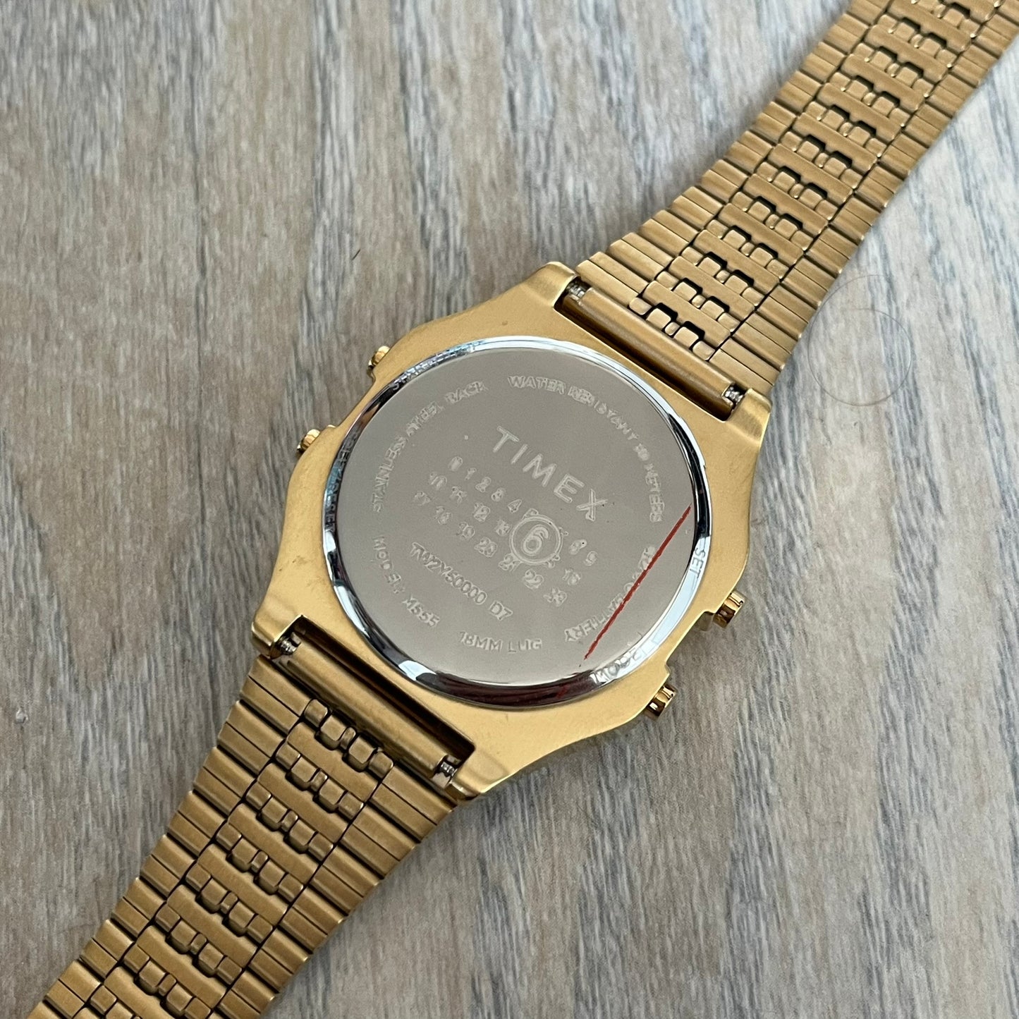 Timex x Maison Margiela MM6 Gold Watch + Bracelet Gift Set TWG067500QY is a collaborative reinterpretation of the classic Timex T80, released on October 24, 2024. Crafted from polished and brushed stainless steel, it features a 36mm digital case with Timex branding and a distinctive 0–23 numeral layout, including a subtle circled “6” nod to MM6 design language. The watch offers 100 ft water resistance, mineral glass, backlight, alarm, timer, and date functions, and is presented as a 2-in-1 gift set with an 
