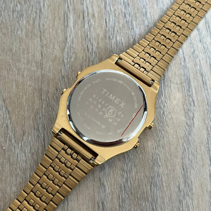 Timex x Maison Margiela MM6 Gold Watch + Bracelet Gift Set TWG067500QY is a collaborative reinterpretation of the classic Timex T80, released on October 24, 2024. Crafted from polished and brushed stainless steel, it features a 36mm digital case with Timex branding and a distinctive 0–23 numeral layout, including a subtle circled “6” nod to MM6 design language. The watch offers 100 ft water resistance, mineral glass, backlight, alarm, timer, and date functions, and is presented as a 2-in-1 gift set with an 
