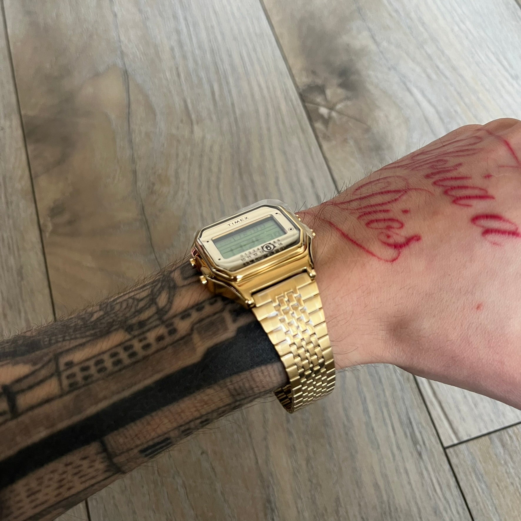 Timex x Maison Margiela MM6 Gold Watch + Bracelet Gift Set TWG067500QY is a collaborative reinterpretation of the classic Timex T80, released on October 24, 2024. Crafted from polished and brushed stainless steel, it features a 36mm digital case with Timex branding and a distinctive 0–23 numeral layout, including a subtle circled “6” nod to MM6 design language. The watch offers 100 ft water resistance, mineral glass, backlight, alarm, timer, and date functions, and is presented as a 2-in-1 gift set with an 
