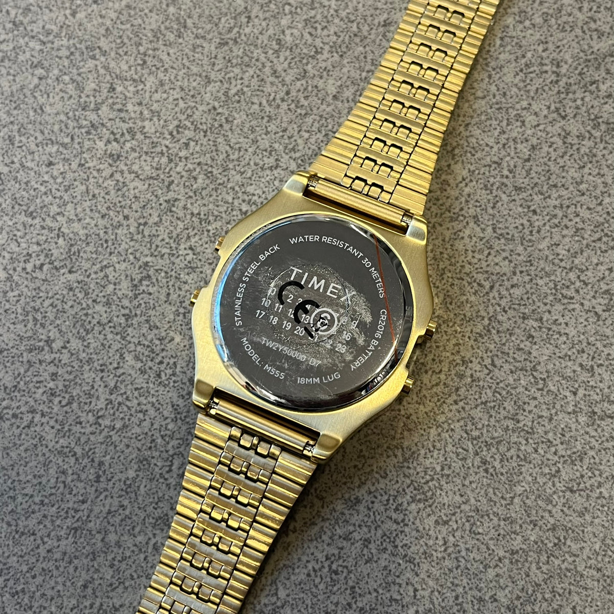 Timex x Maison Margiela MM6 Gold Watch + Bracelet Gift Set TWG067500QY is a collaborative reinterpretation of the classic Timex T80, released on October 24, 2024. Crafted from polished and brushed stainless steel, it features a 36mm digital case with Timex branding and a distinctive 0–23 numeral layout, including a subtle circled “6” nod to MM6 design language. The watch offers 100 ft water resistance, mineral glass, backlight, alarm, timer, and date functions, and is presented as a 2-in-1 gift set with an 