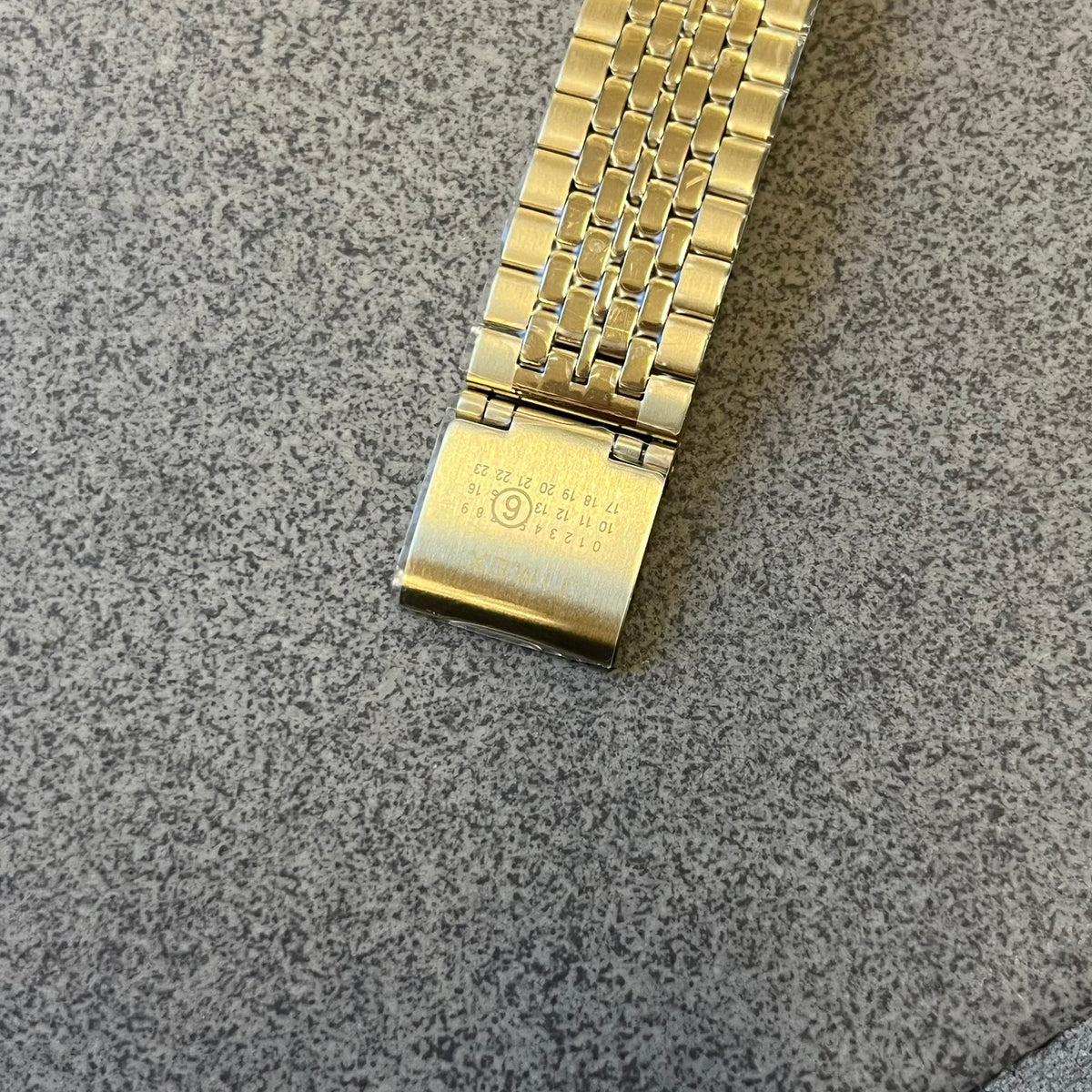 Timex x Maison Margiela MM6 Gold Watch + Bracelet Gift Set TWG067500QY is a collaborative reinterpretation of the classic Timex T80, released on October 24, 2024. Crafted from polished and brushed stainless steel, it features a 36mm digital case with Timex branding and a distinctive 0–23 numeral layout, including a subtle circled “6” nod to MM6 design language. The watch offers 100 ft water resistance, mineral glass, backlight, alarm, timer, and date functions, and is presented as a 2-in-1 gift set with an 