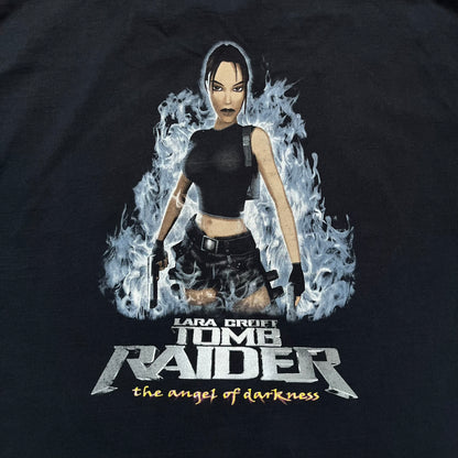 Tomb Raider: The Angel of Darkness 2003 Tee is a black washed T-shirt featuring a small game logo on the front chest. The back displays a large graphic based on the game cover, with Lara Croft in front of a flame rendered in early 3D-style artwork, with the game title printed below.
