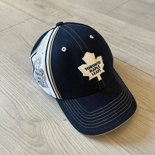 Navy blue cap with Toronto Maple Leafs logo on a wooden floor