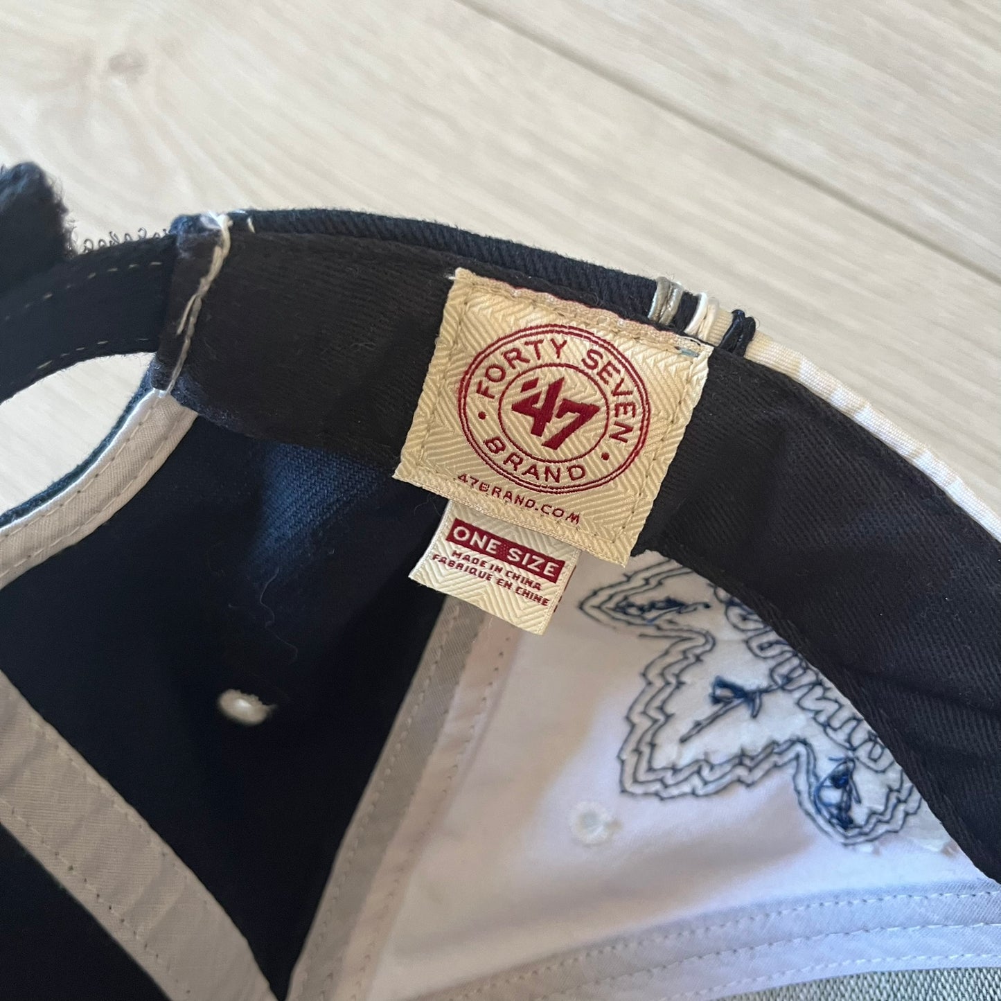 Close-up of a cap with a 'Forty Seven Brand' tag on a textured surface