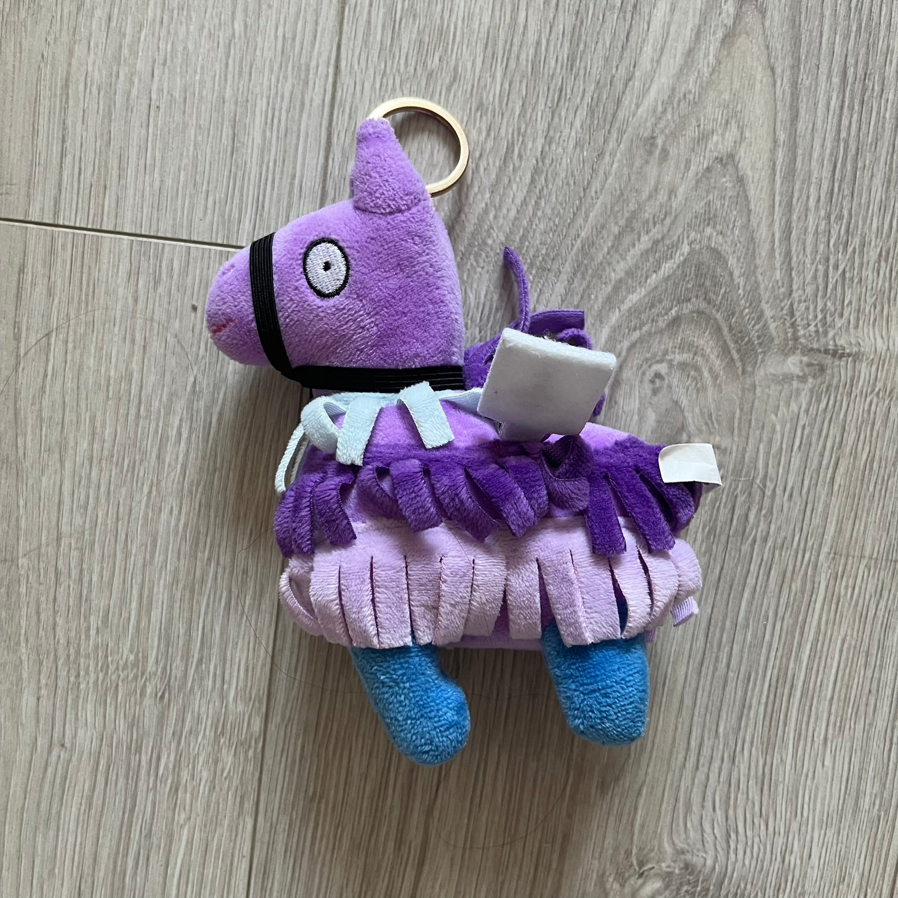 Purple plush keychain with a character design on a wooden surface
