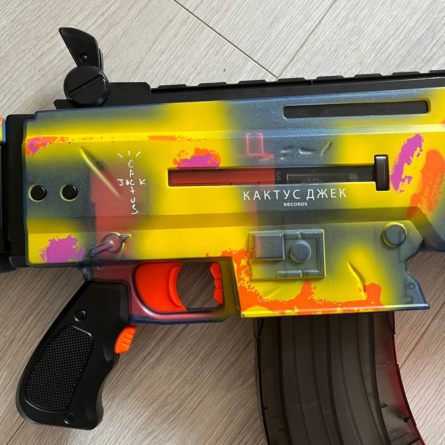 Colorful toy gun with 'Kaktus Jack' branding on a wooden surface