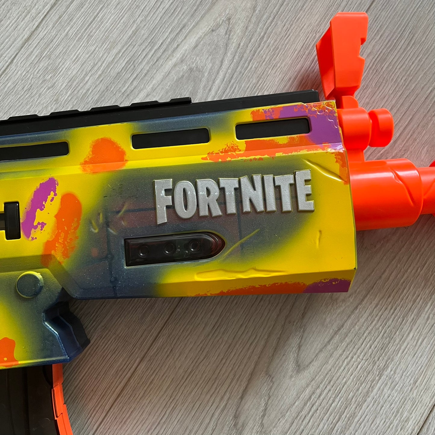 Colorful toy gun with 'Fortnite' branding on a wooden surface