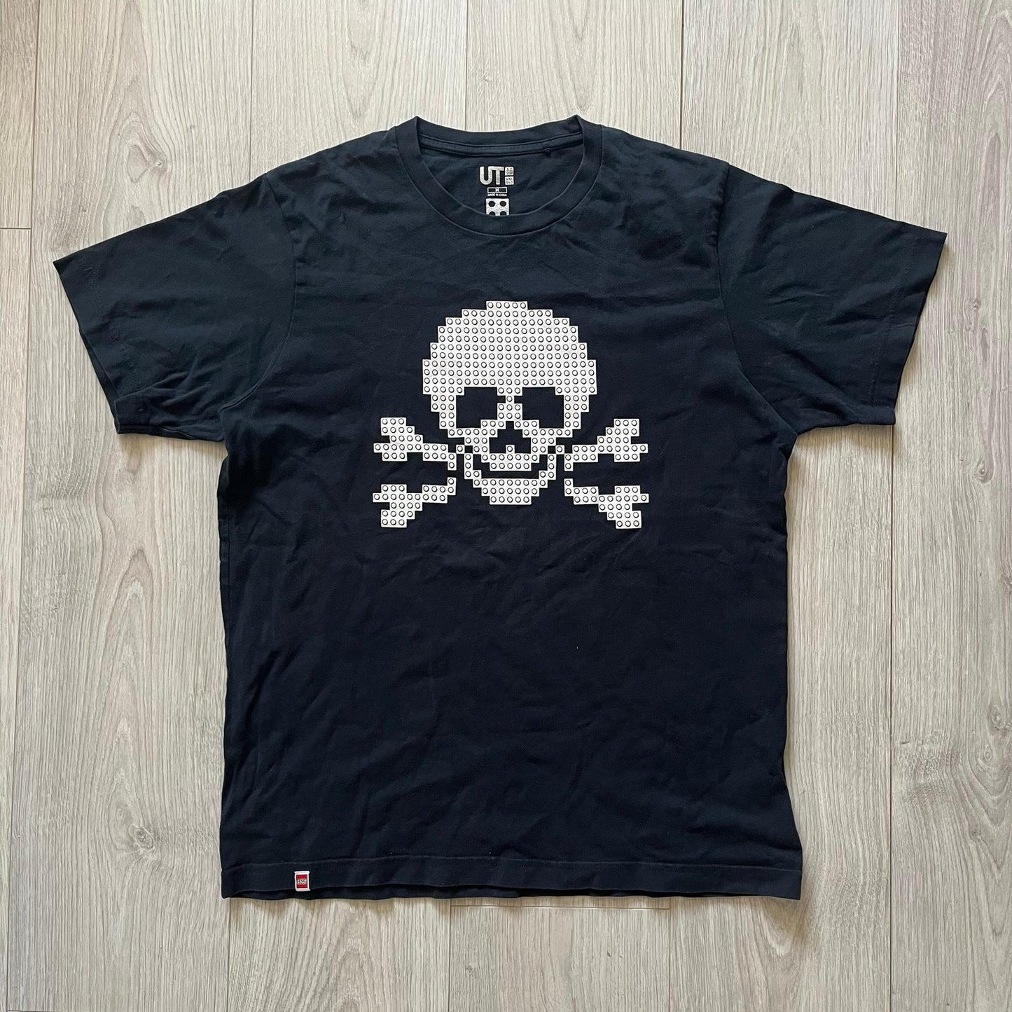 Black boxer briefs with a white pixelated skull design on a wooden floor.